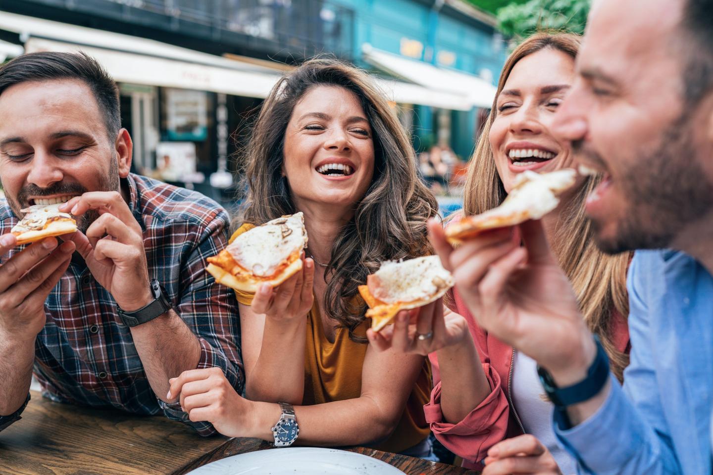 Group of happy young friends eating pizza together