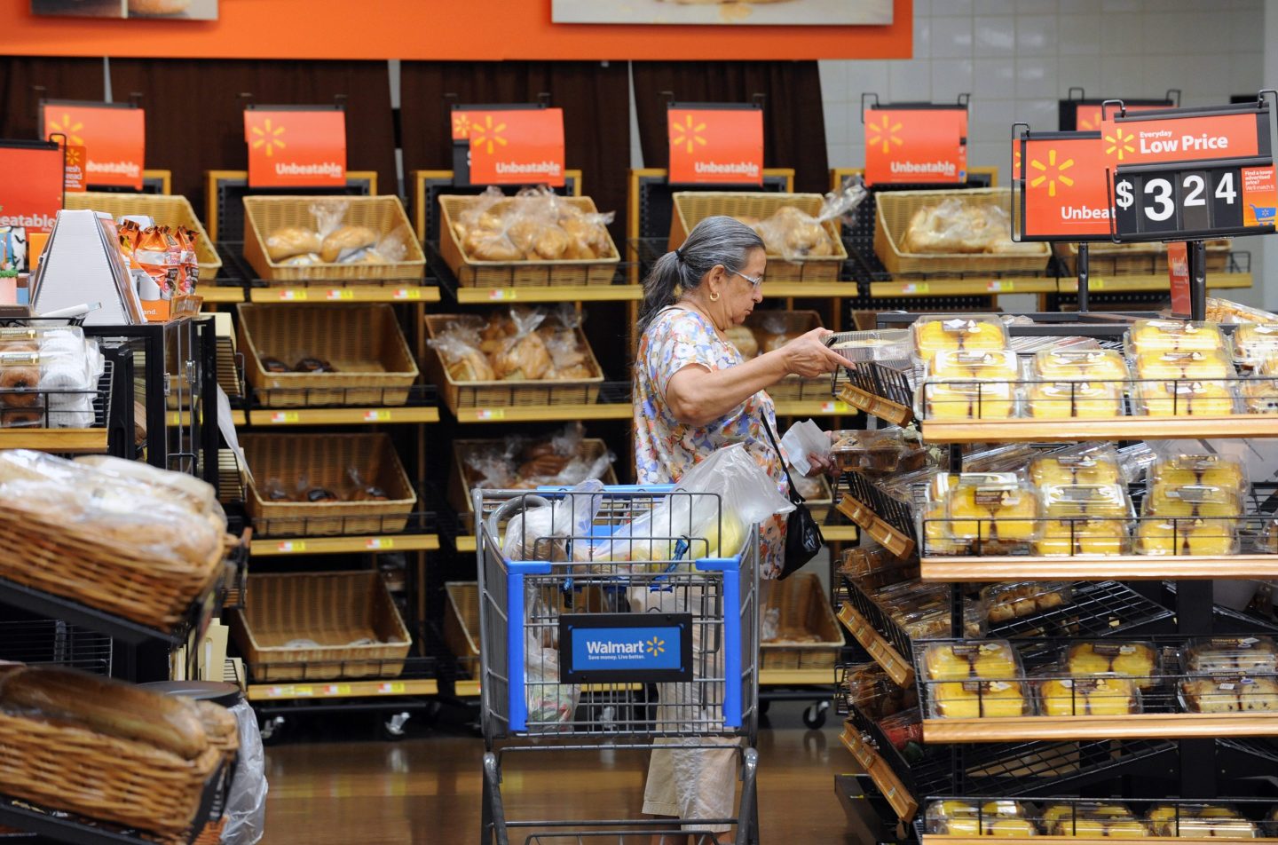 A woman looks at a shelf of baked goods in a Walmart bakery.
