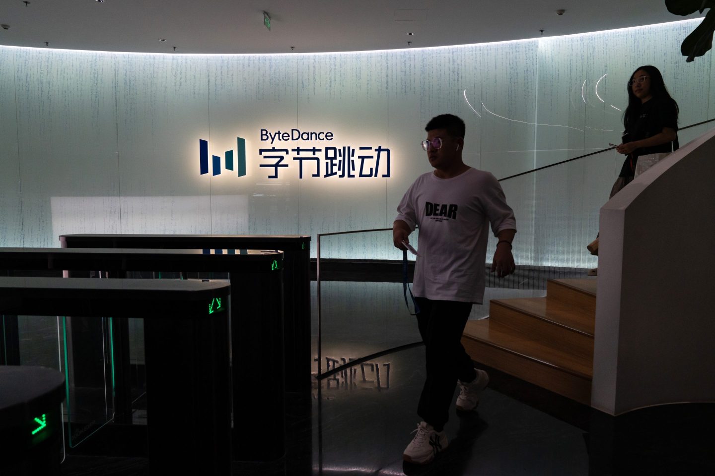 A man walks down the stairs lite up with a "ByteDance" sign above it.