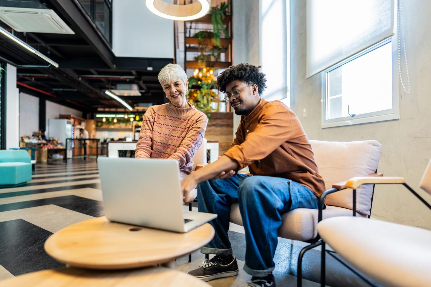 woman talking with a young man while use laptop at office