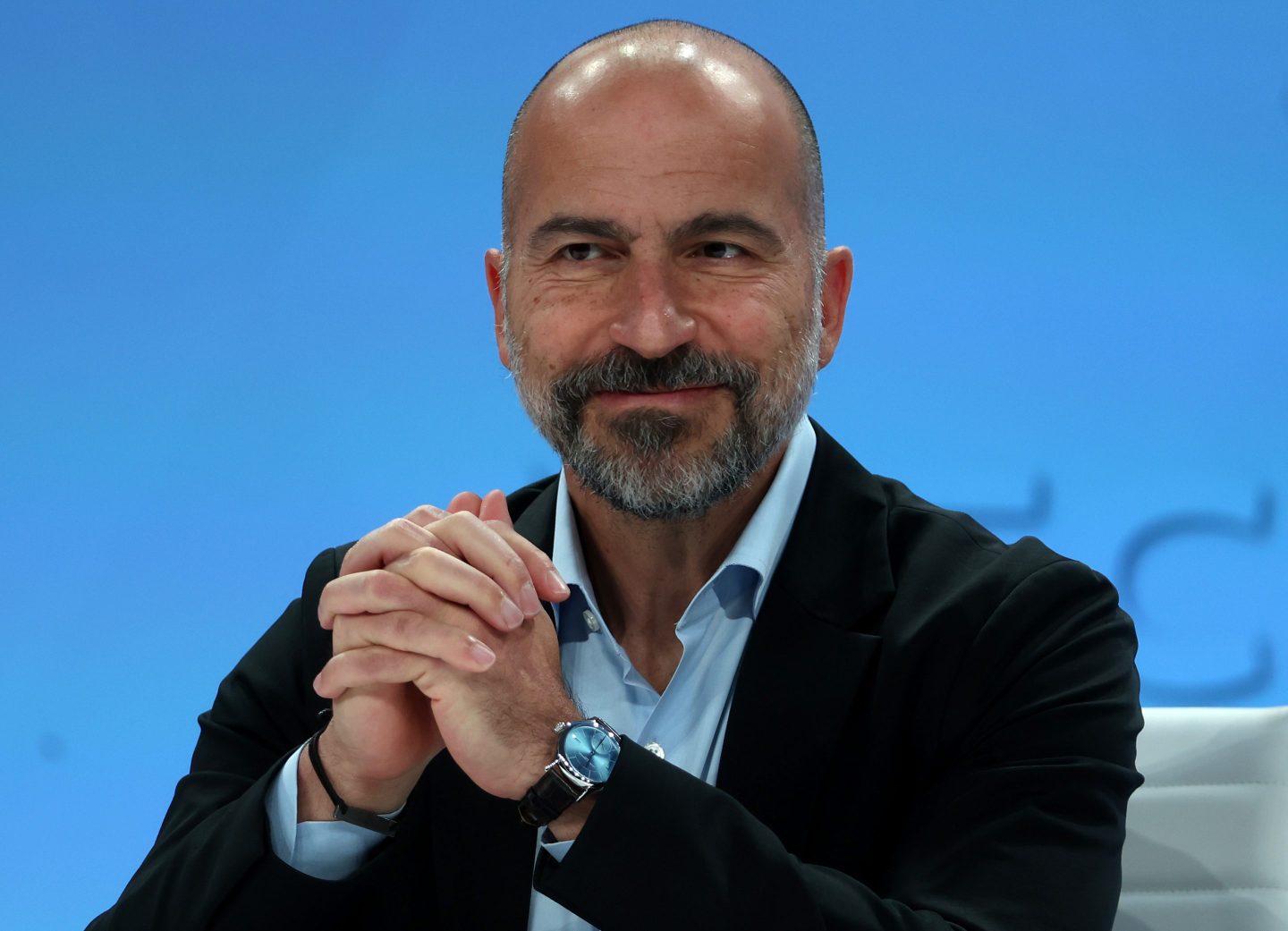 Dara Khosrowshahi smile with his hands clasped in front of him.