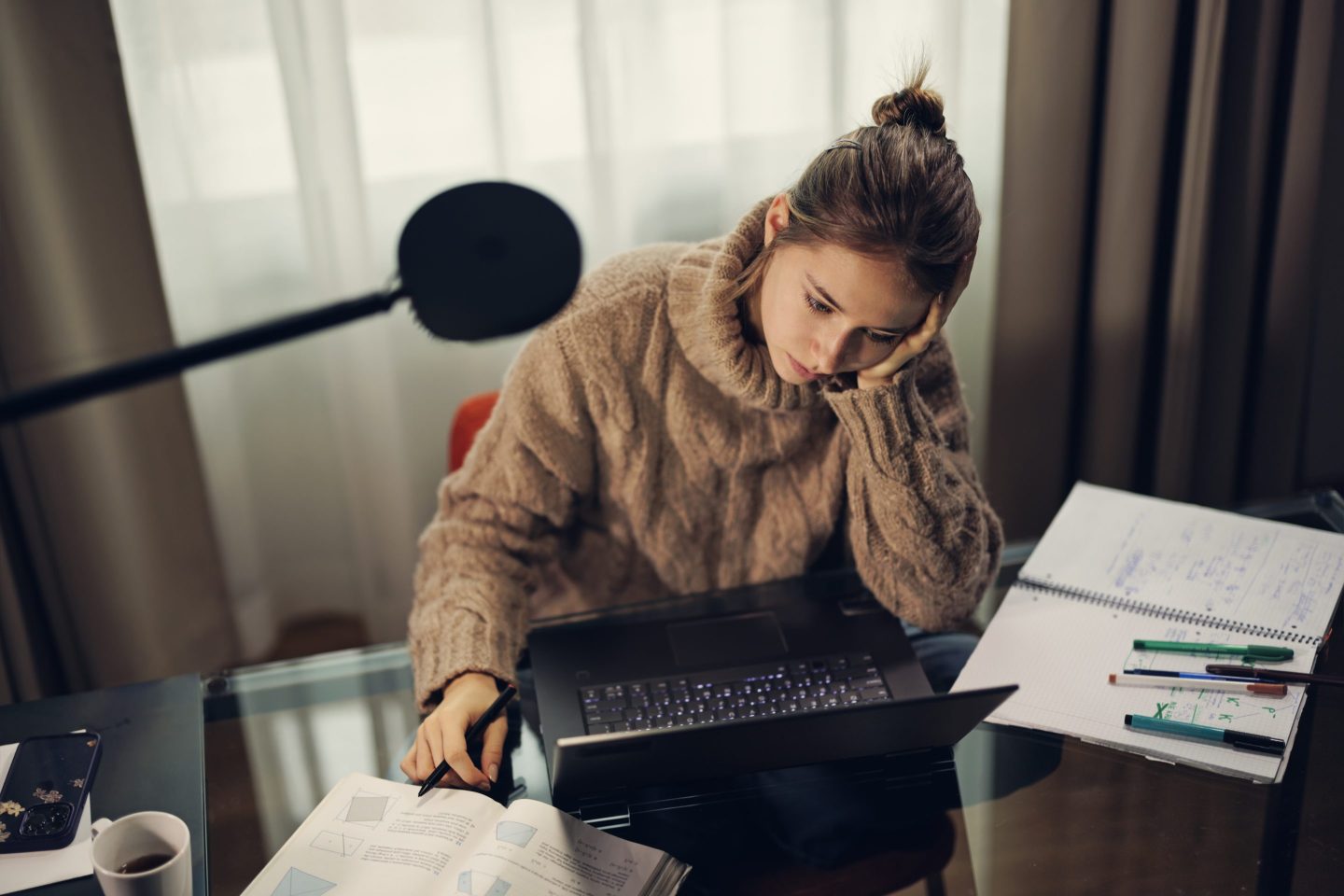 A young woman works at a desk.
