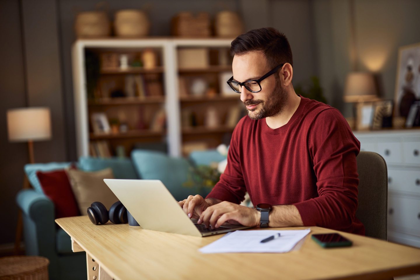 A man sits at a table typing on his laptop.