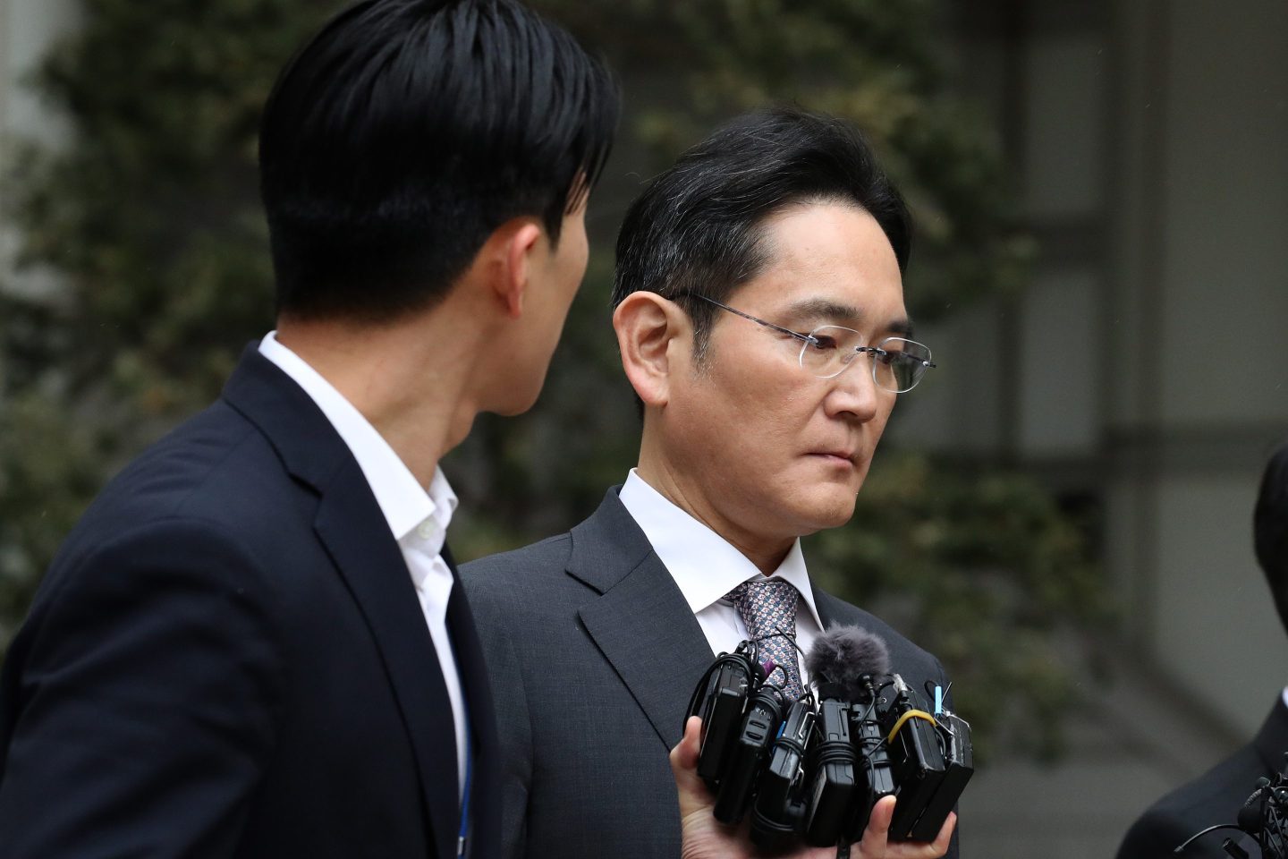 Samsung executive chairman Lee Jae-yong looks downcast and averts his eyes from someone holding a bundle of recorders as he exits a courthouse.