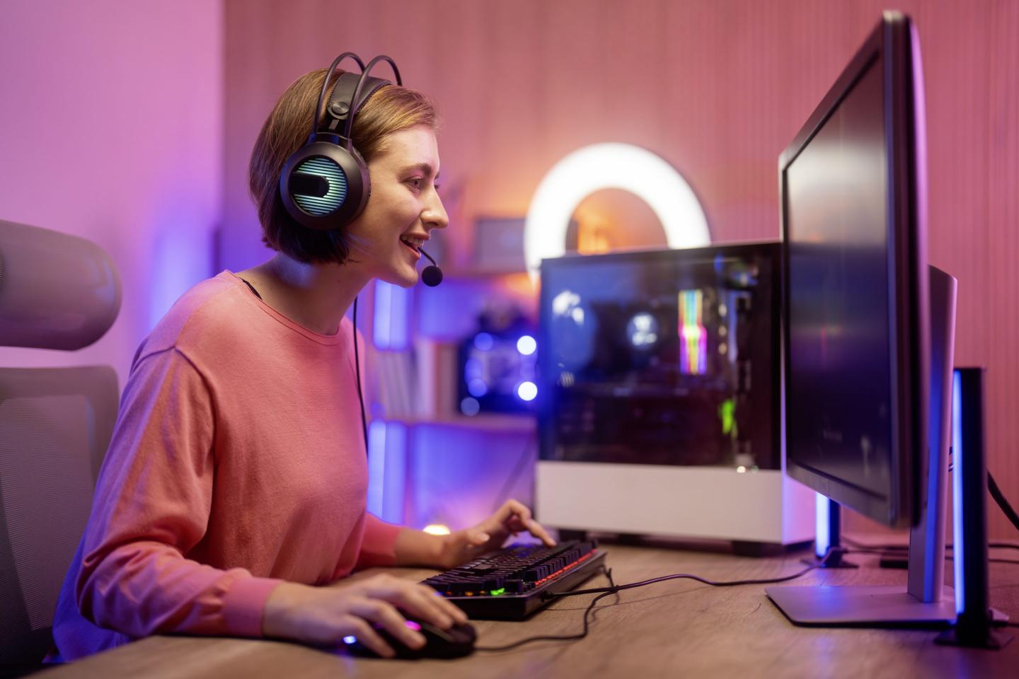 Female gamer sits in front of gaming monitor with headphones on