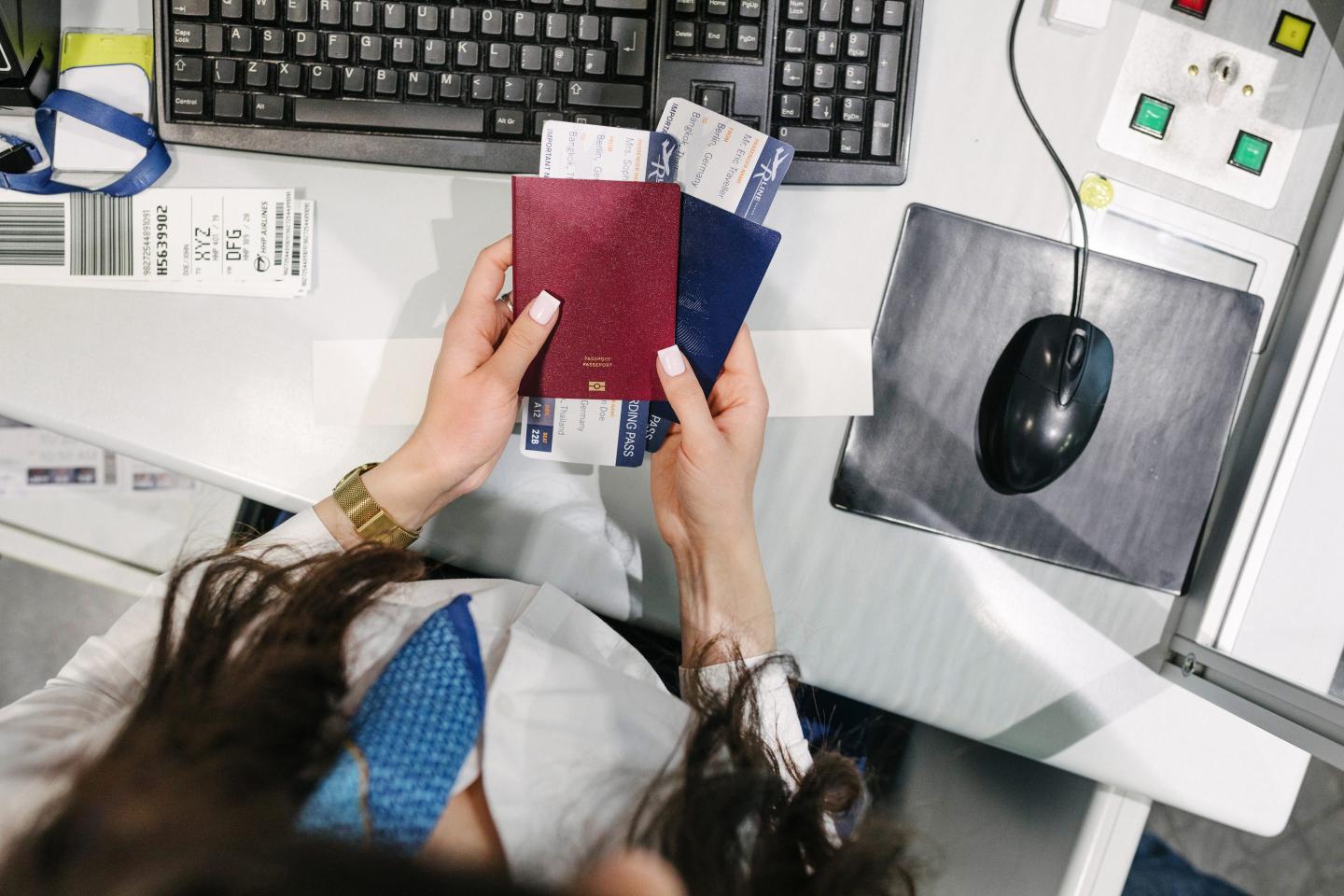High Angle View Of Airport Staff Holding Passports And Boarding Passes