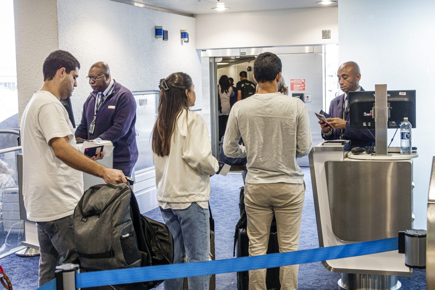 People wait on line at an airport gate to board the plane