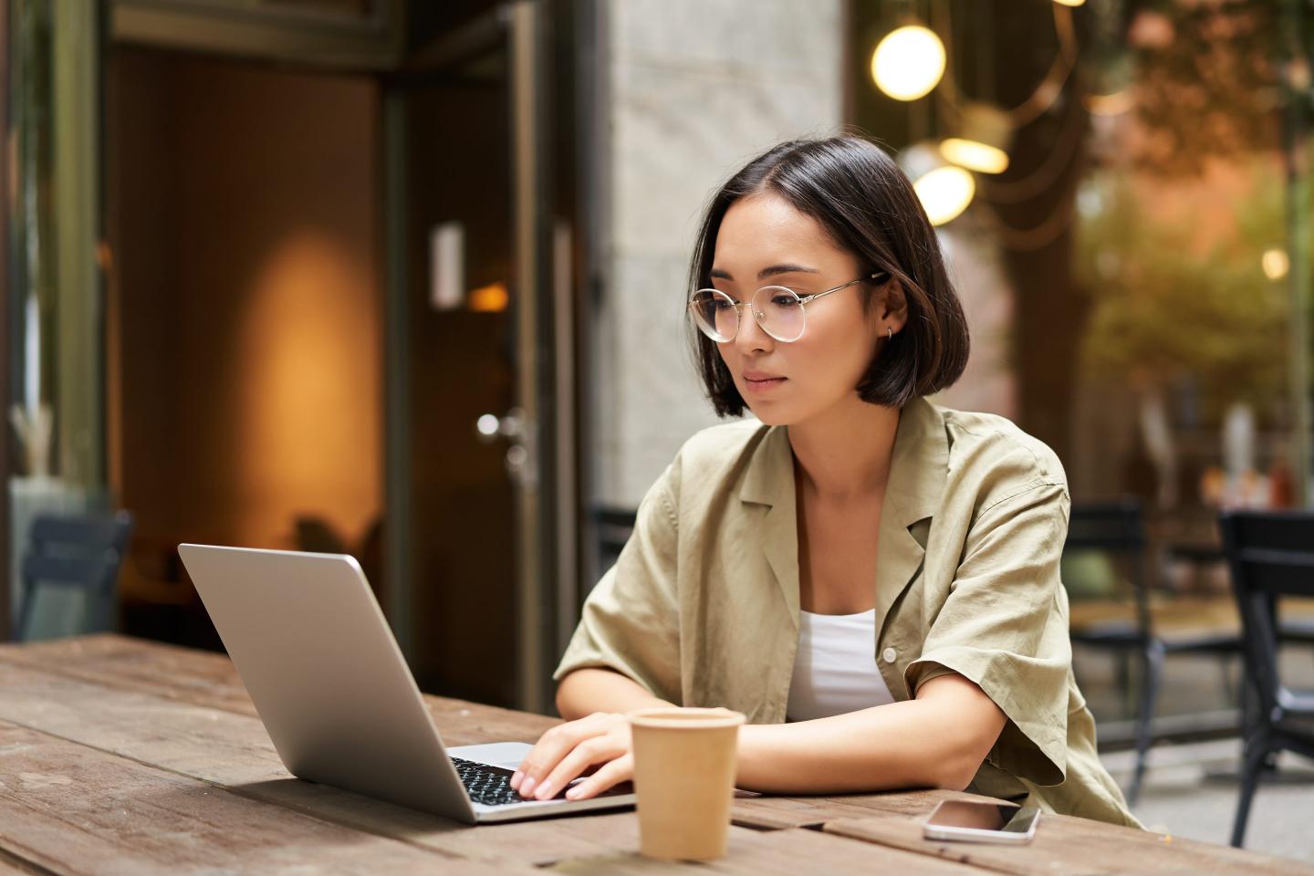A woman sits at a long table on her computer.
