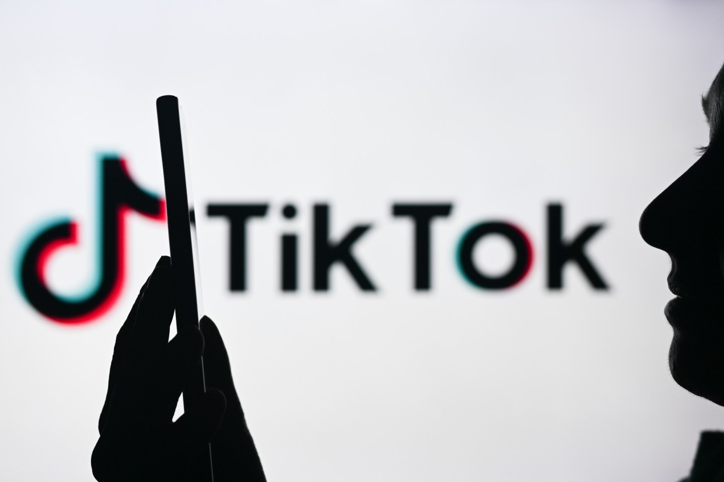 A person holding a phone in front of a large TikTok logo