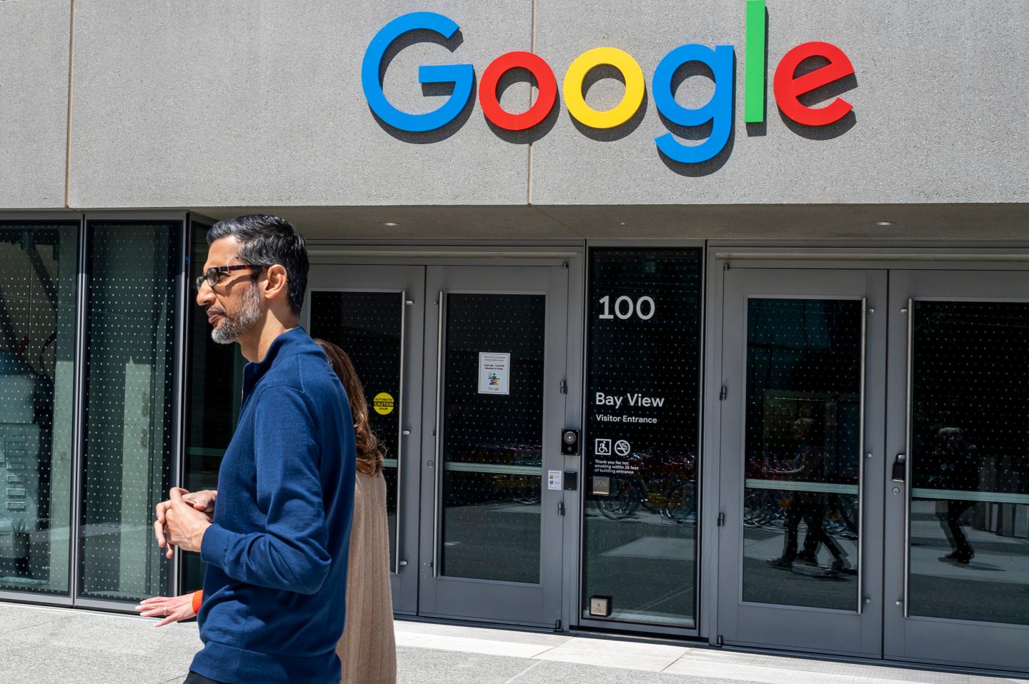 Photo of Sundar Pichai walking past a Google office building