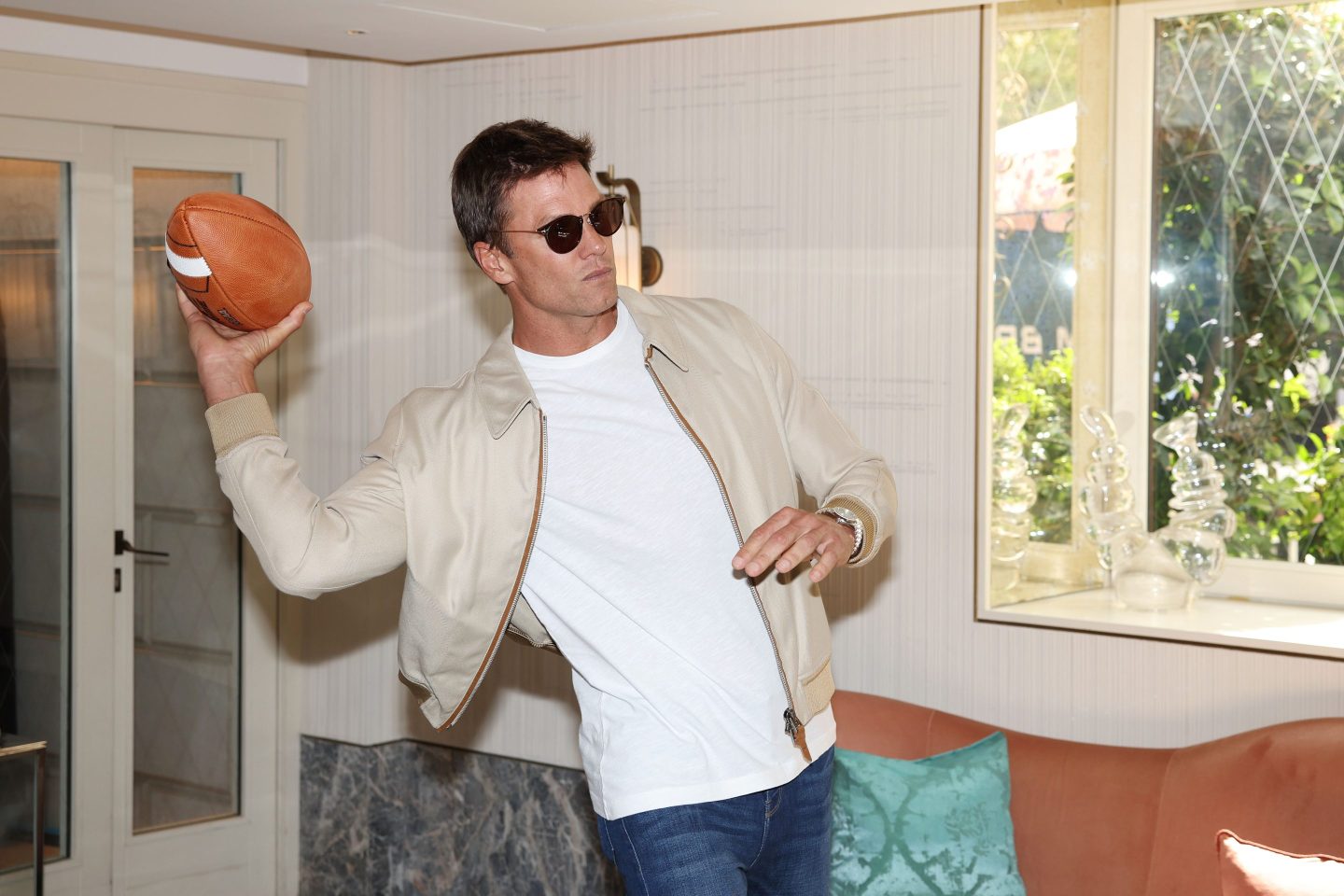 Tom Brady wearing sunglasses throwing a football
