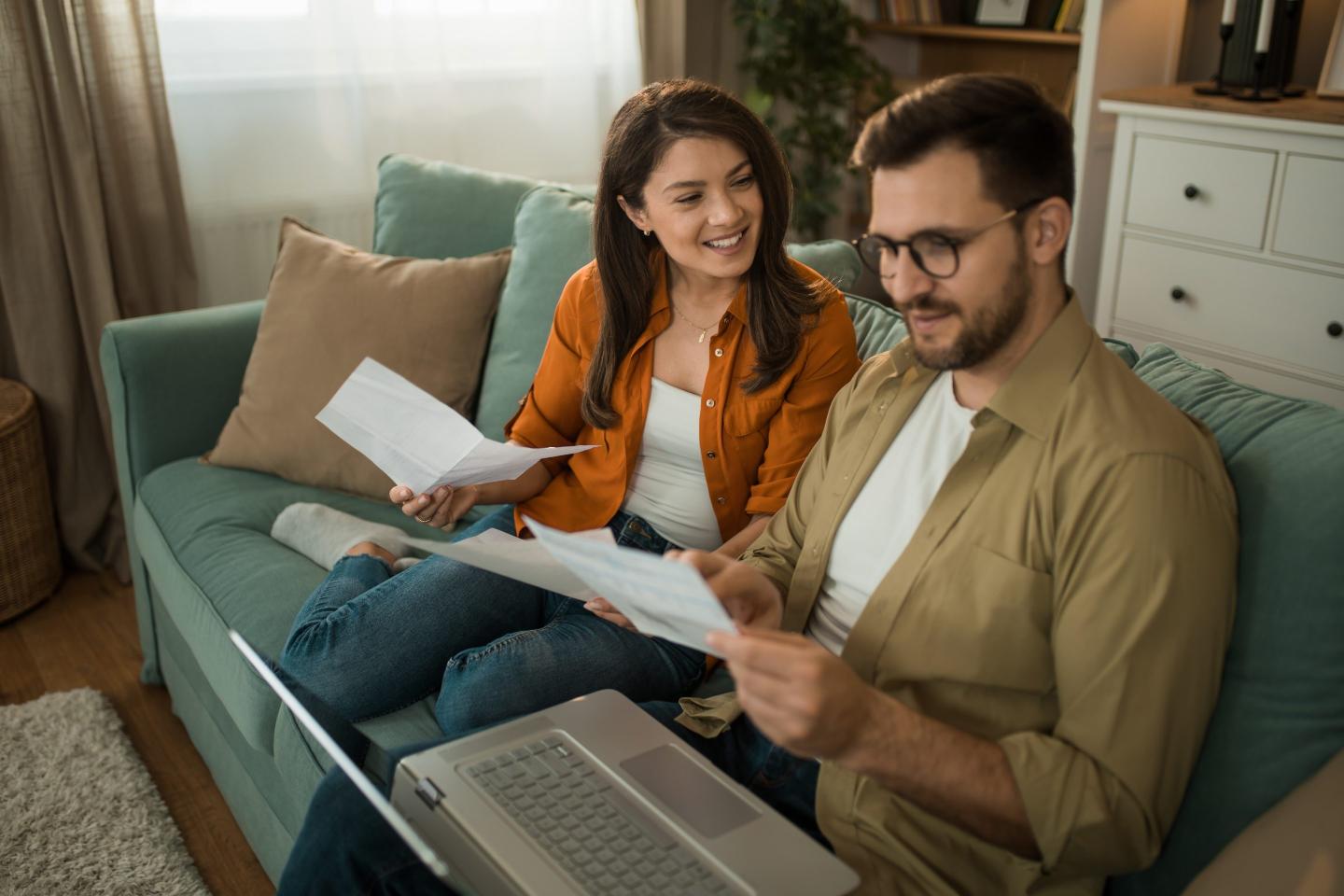 Happy couple talking about their financial bills at home.