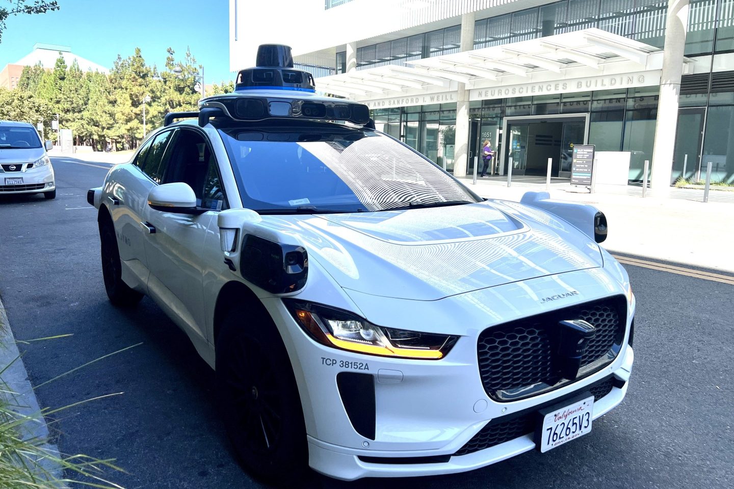A Waymo self-driving car sits parked in the shade