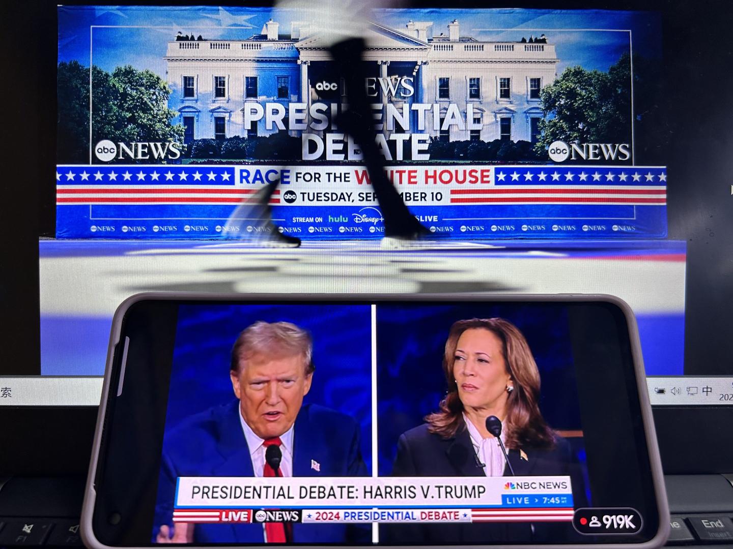 A smartphone screen shows the live broadcast of presidential debate between Vice President Kamala Harris and former President Donald Trump