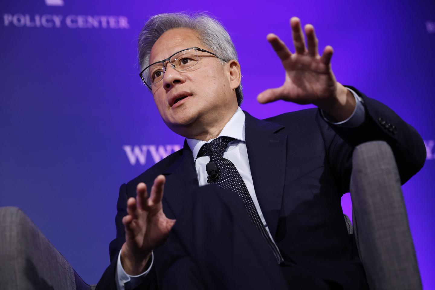 Jensen Huang raises his hands and looks intently as he speaks at a conference.