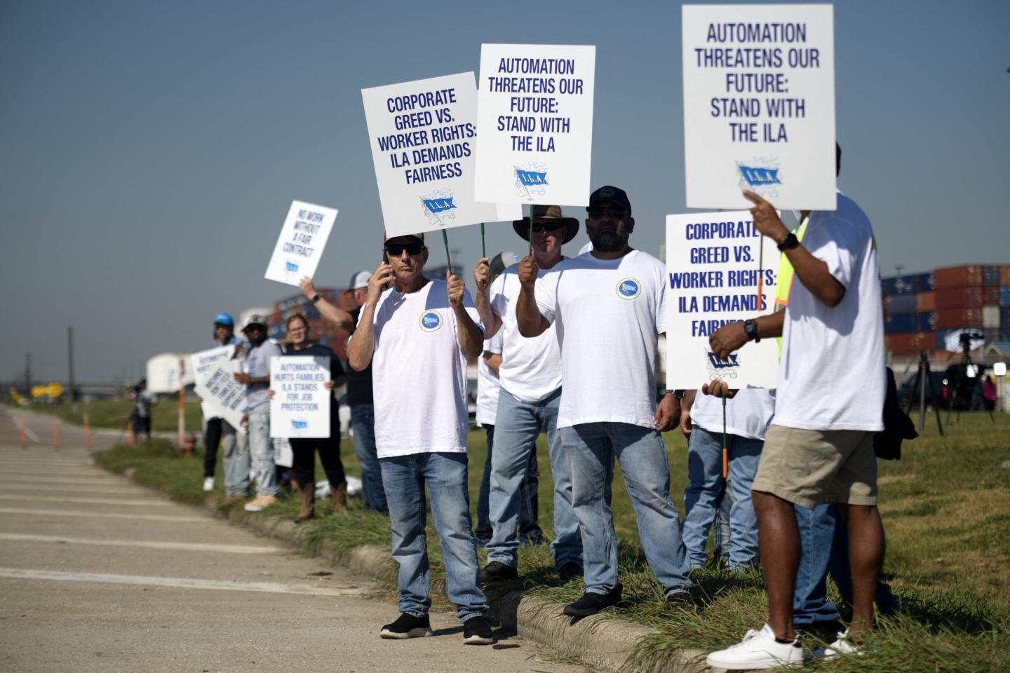 dockworkers picket with signs that read "automation threatens our future: stand with the ila"