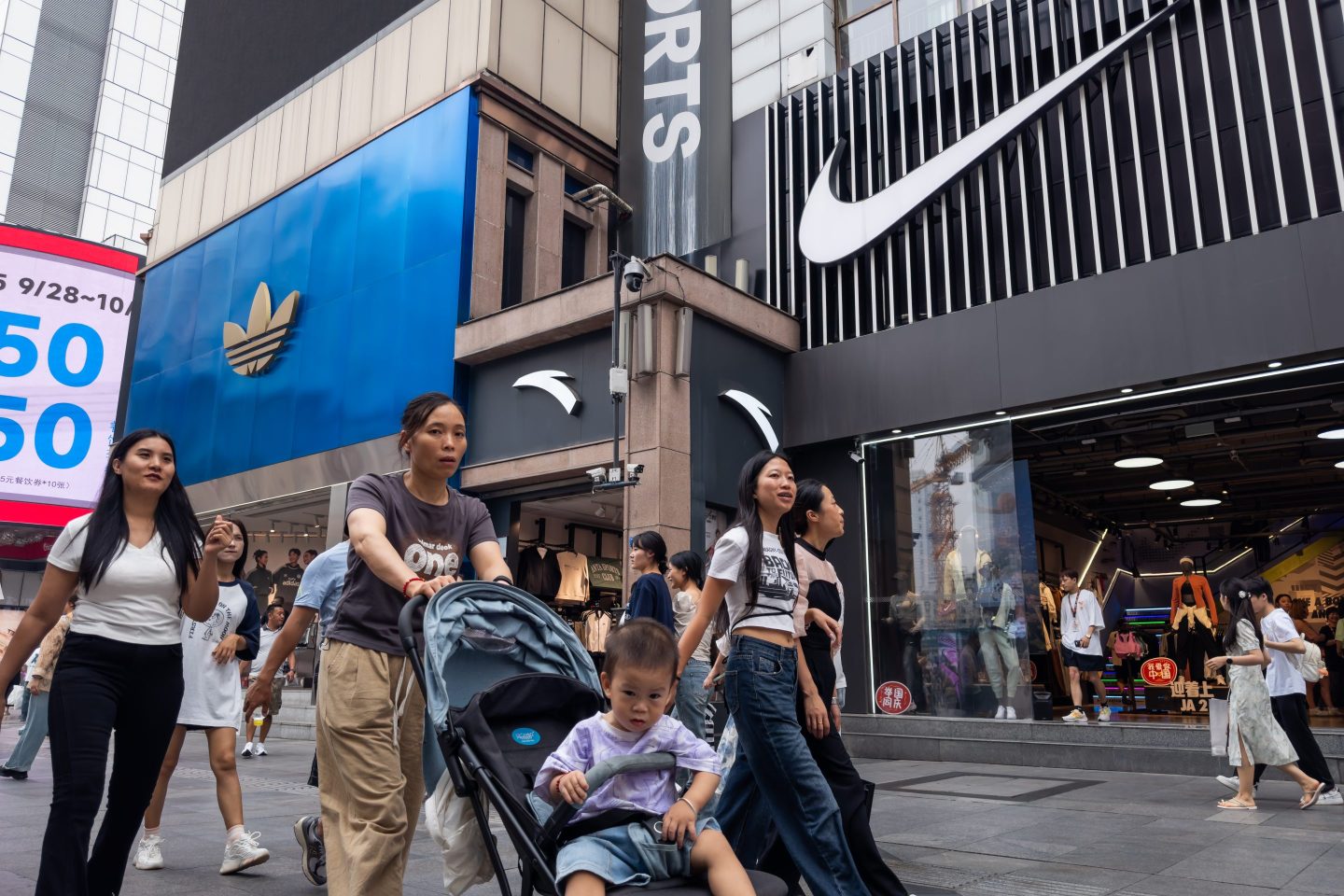 Shoppers and families walk past stores for Nike, Adidas and Chinese brand Anta.