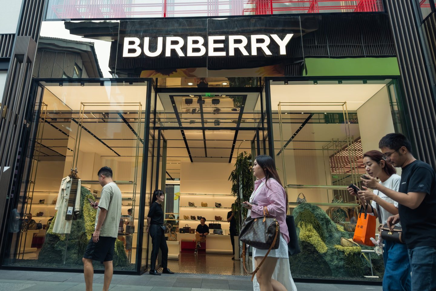 Several pedestrians walk past a Burberry store in Chengdu, with the brand’s distinctive storefront and stylish interior displays visible, on September 28, 2024 in Chengdu, China.