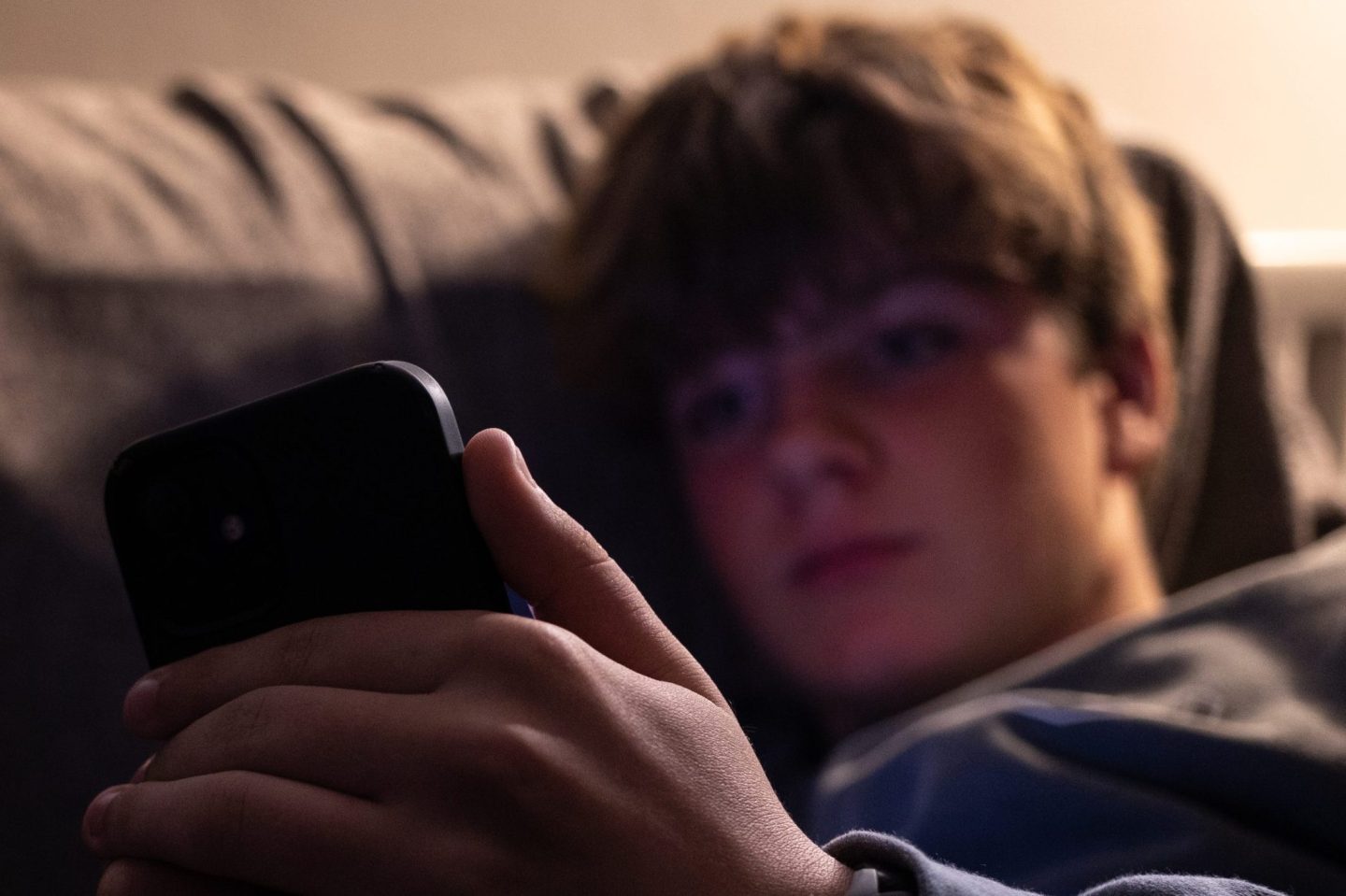 A teenage boy looks at his phone