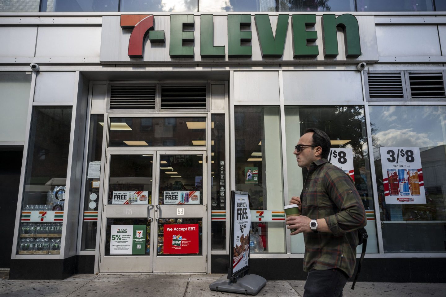 A person walks past a 7-Eleven convenience store