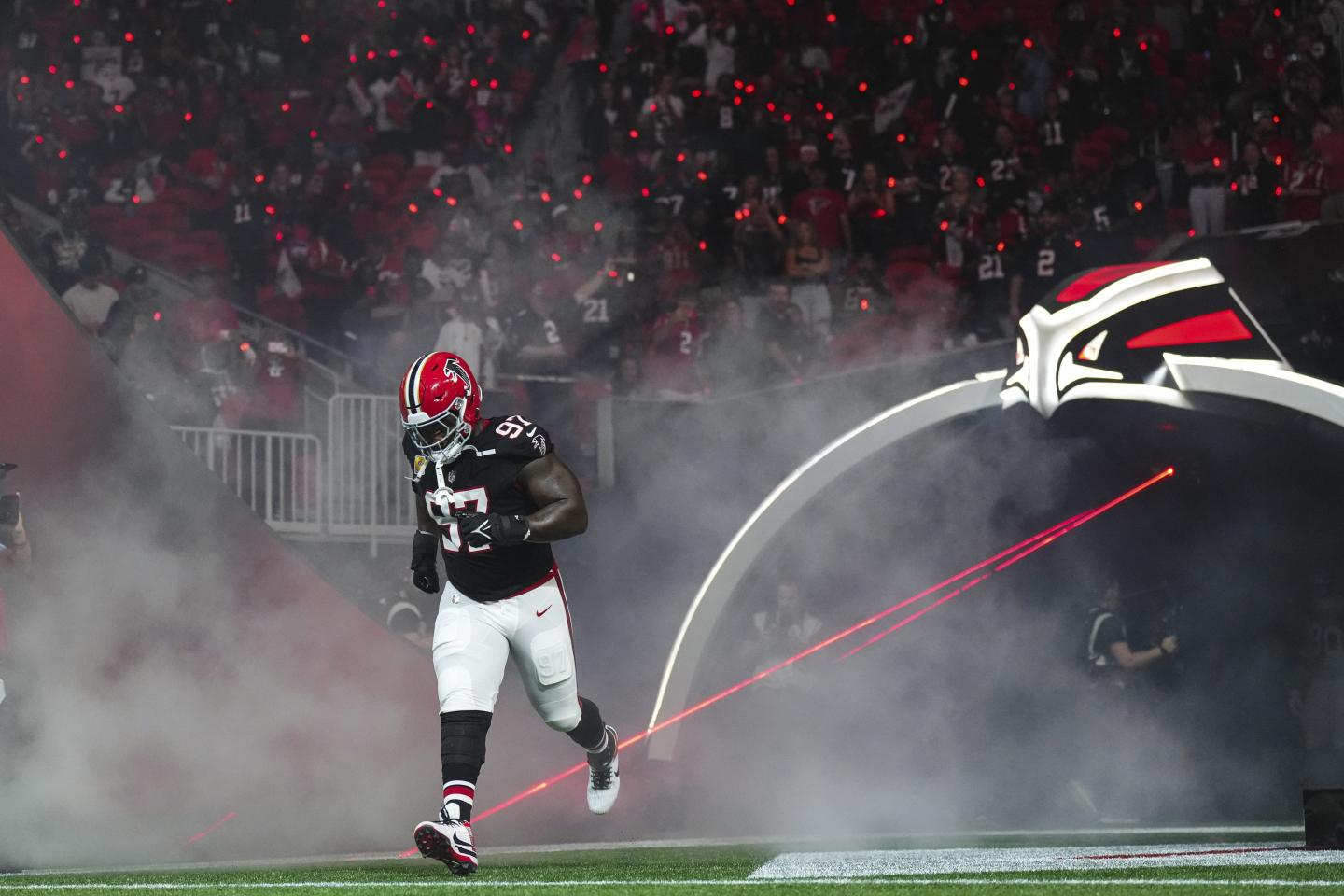 An Atlanta Falcons player runs out of the tunnel with smoke behind him