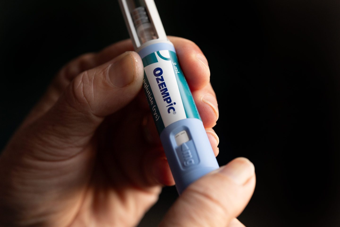 A hand is seen holding Ozempic.