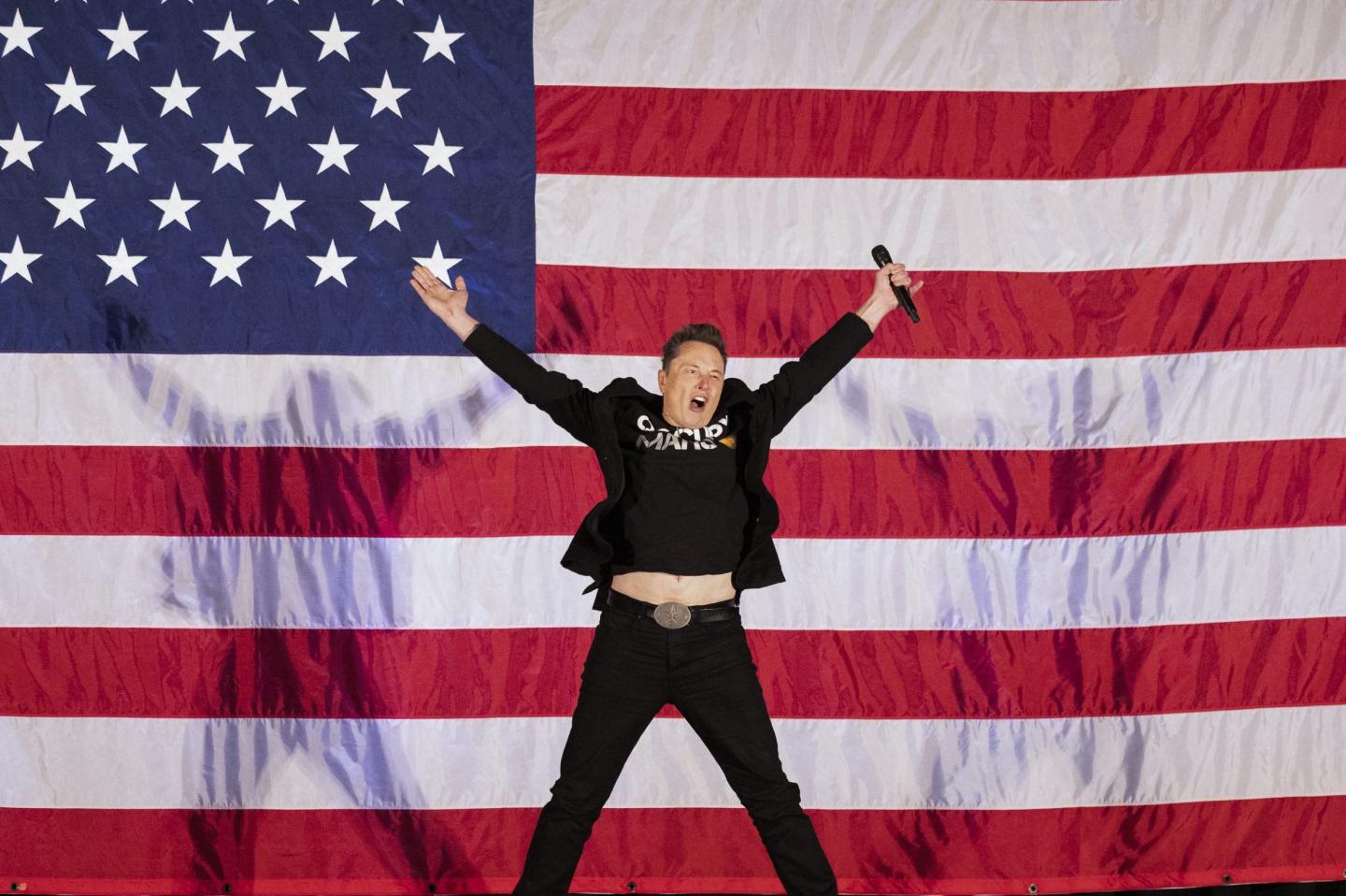 Elon Musk jumps in the air in front of an American flag