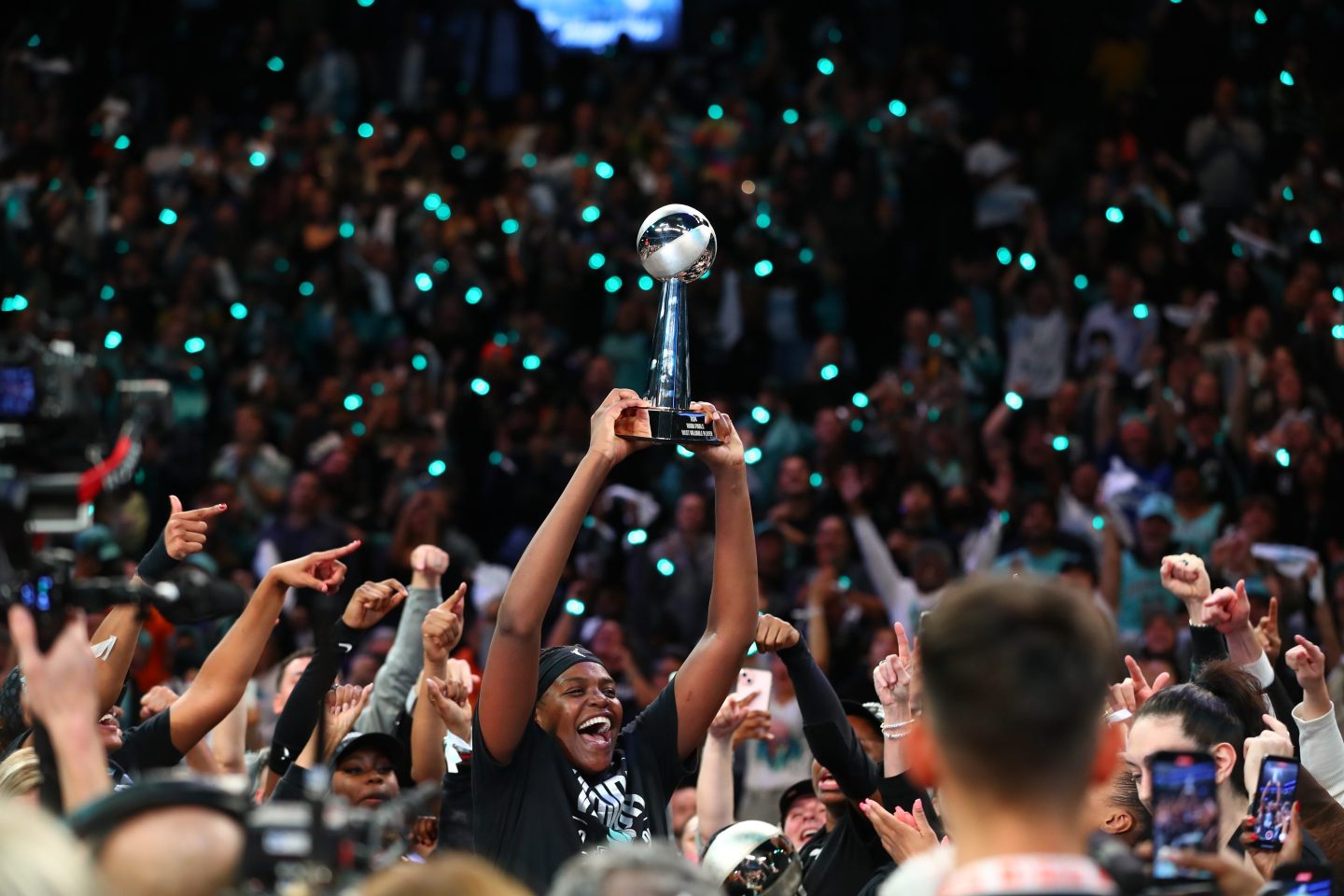 a crowd of basketball players celebrating a win inside a gymnasium