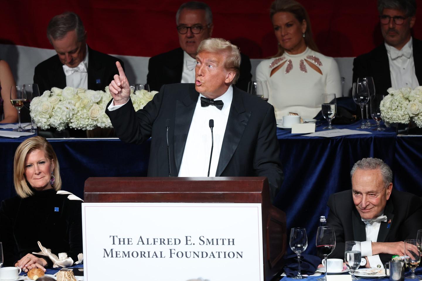 Trump standing at a podium to tell jokes at a campaign dinner