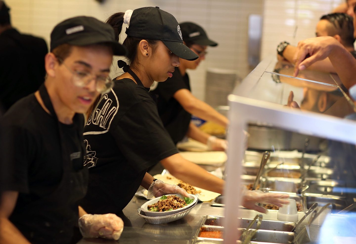 Chipotle workers are seen fulfilling orders.