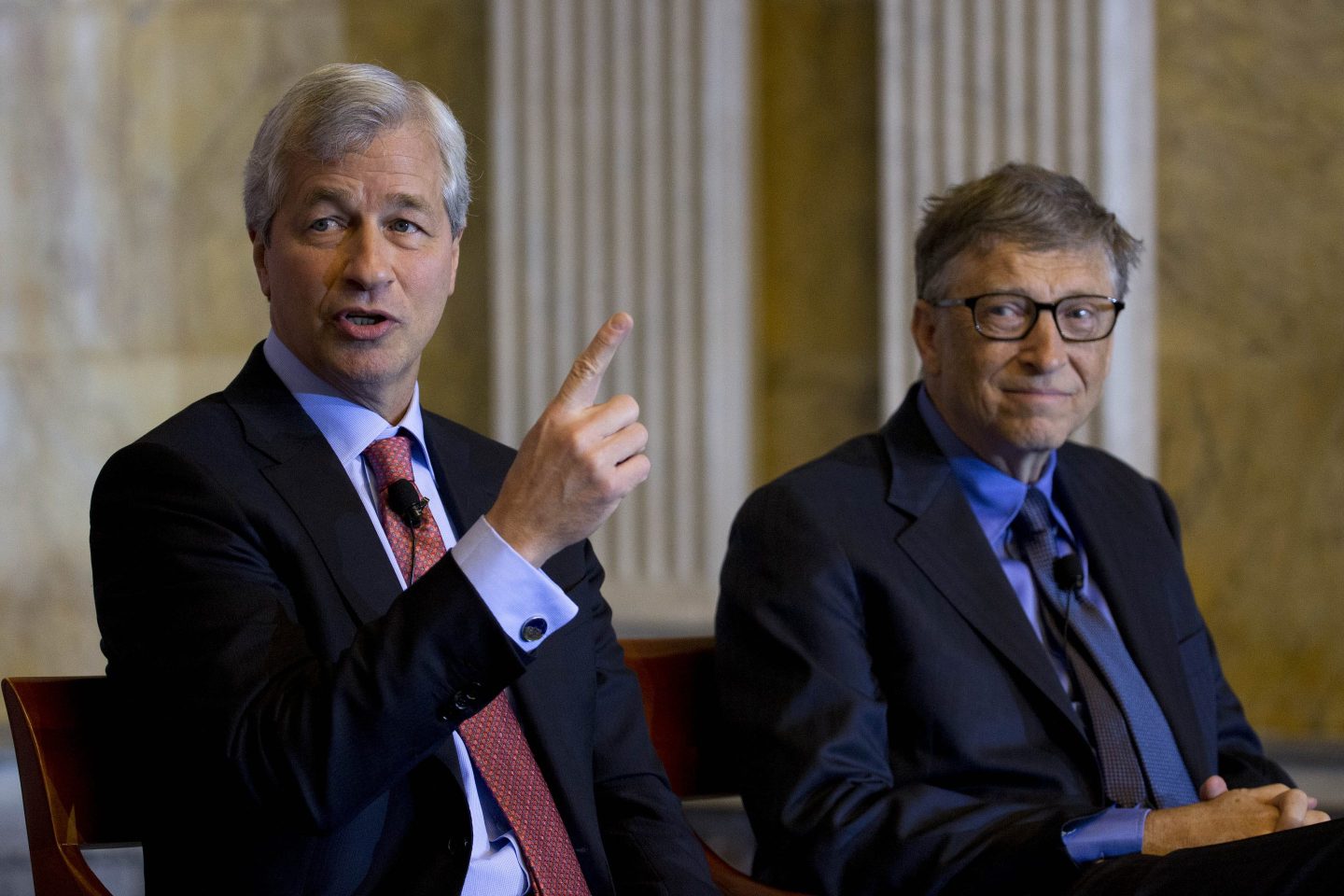 Jamie Dimon and Bill Gates wearing suits and sitting next to each other.