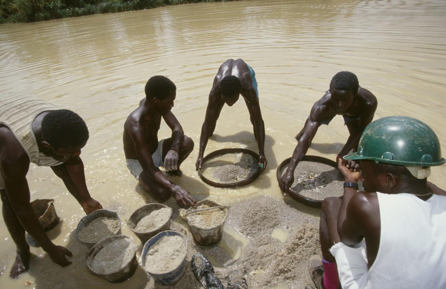 Workers sift for diamonds in a river.