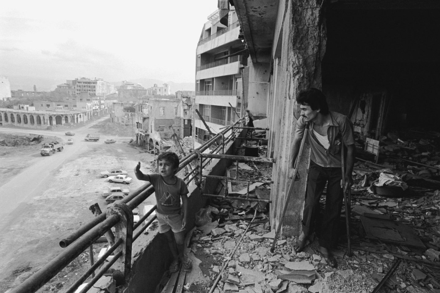 A boy and his father stand in the debris of a destroyed building