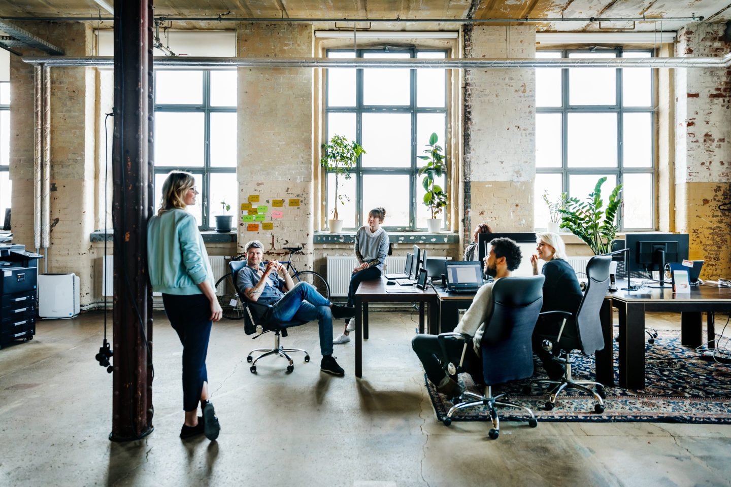 Employees sit and stand around desks at an office