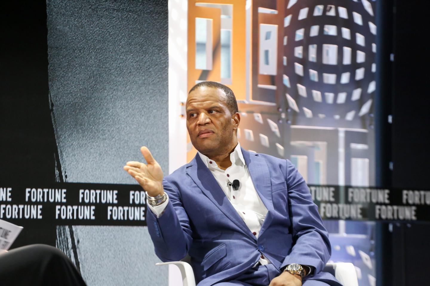 John Hope Bryant gestures to a moderator while speaking on stage
