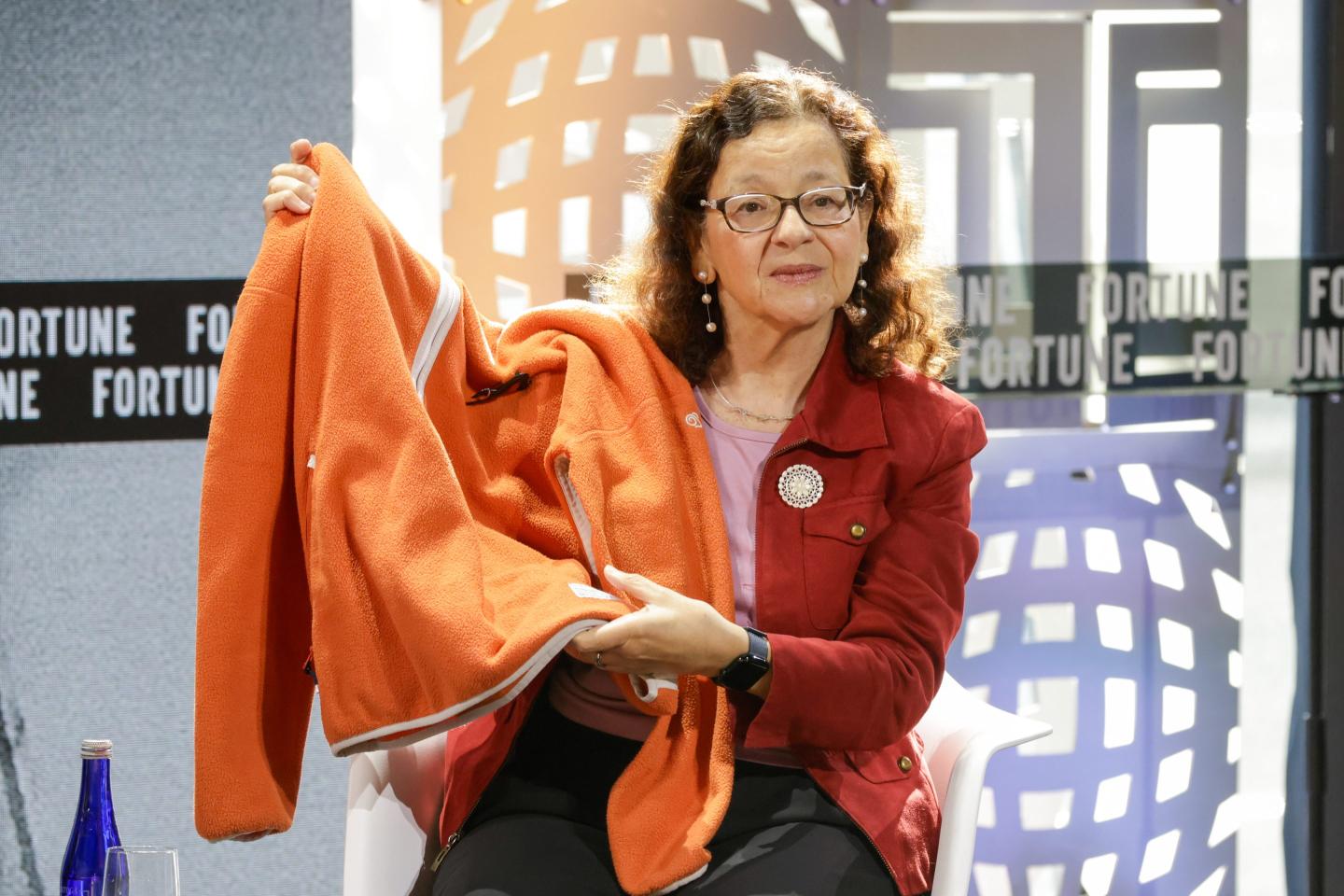 Dr. Jennifer Holmgren holds up an orange jacket, which was converted from pollution using biorecycling