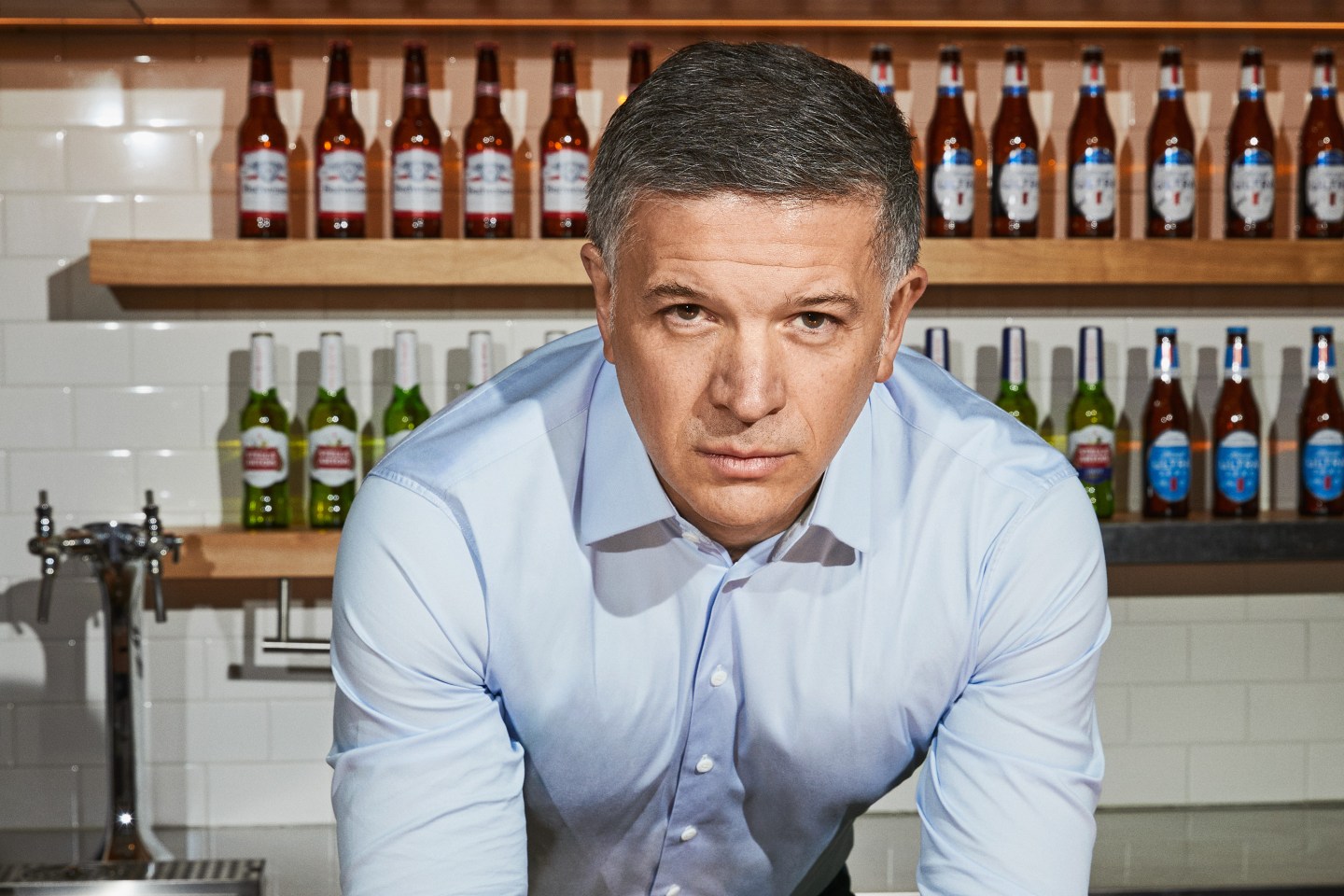 AB InBev CEO Michel Doukeris photographed in front of shelves of beer.