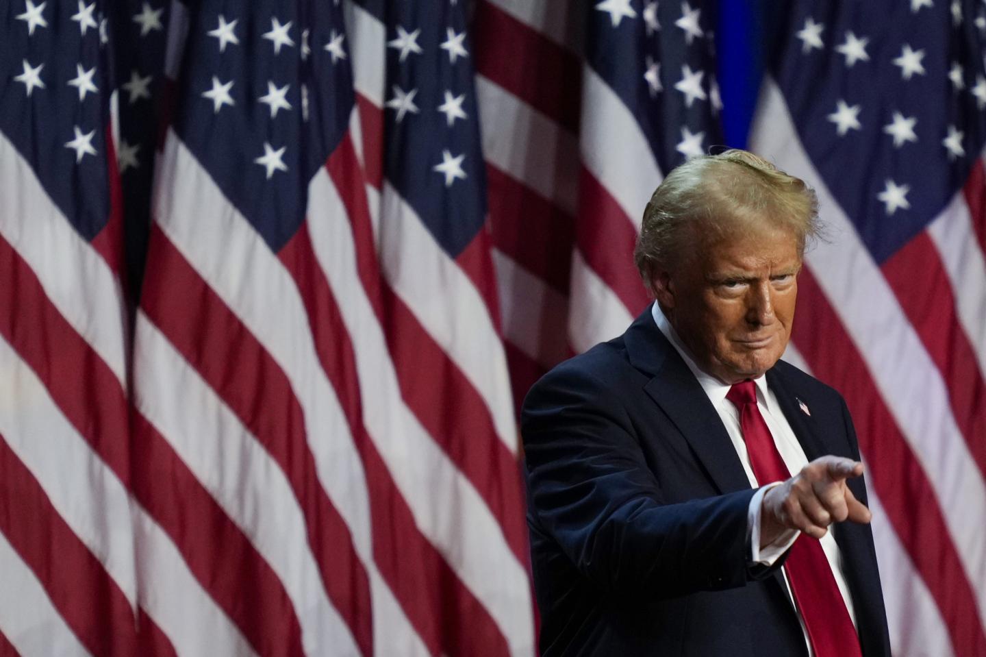 Trump pointing in front of the American flag.