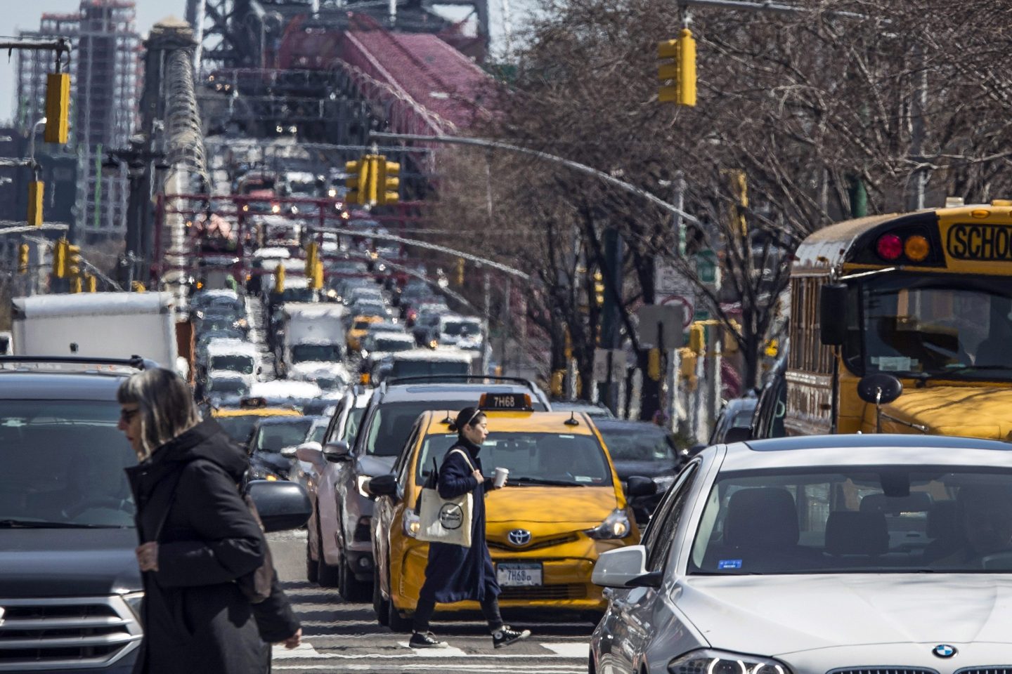 Pedestrians cross Delancey Street as congested traffic from Brooklyn enters Manhattan over the Williamsburg Bridge, March 28, 2019, in New York.