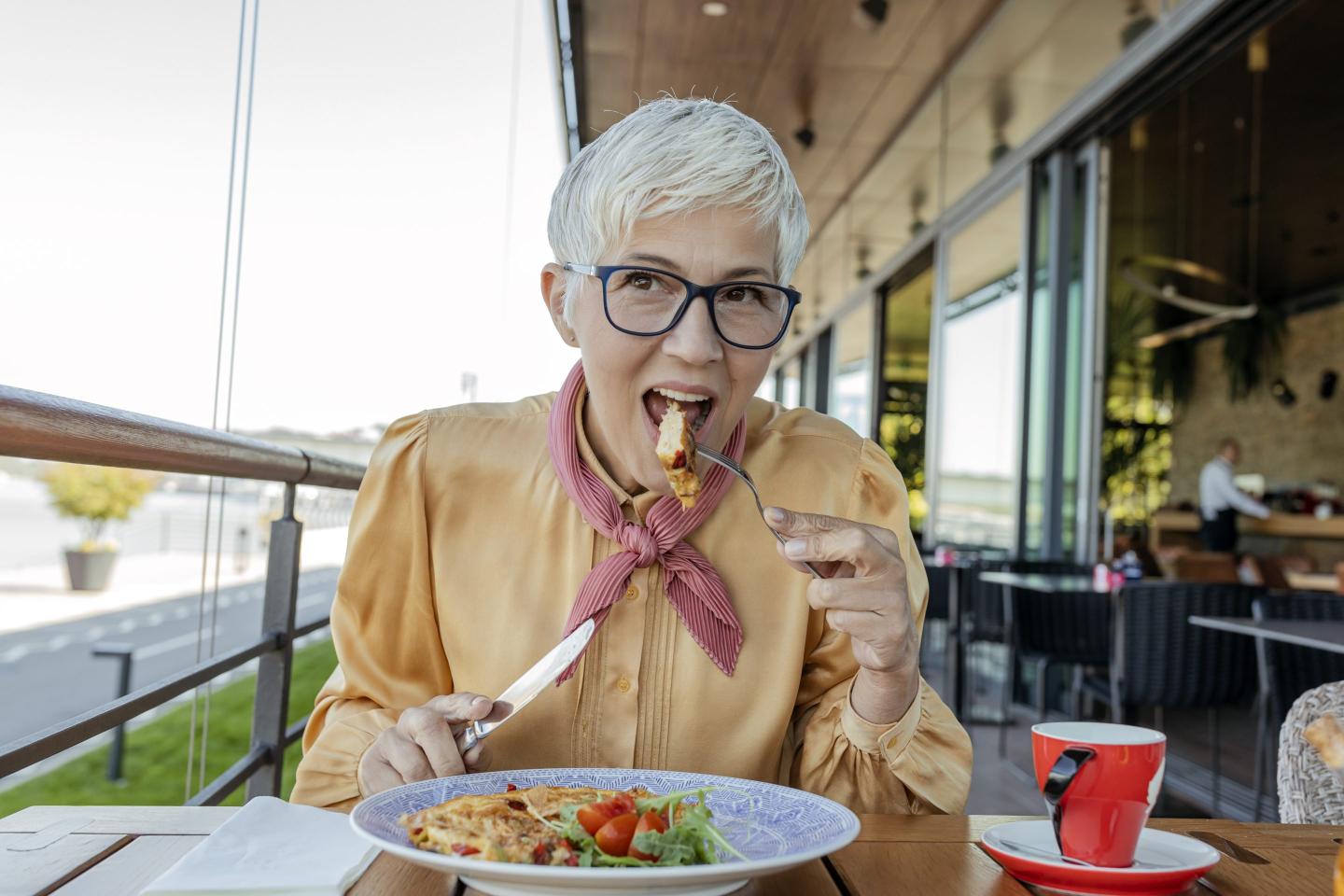 Happy senior woman enjoying in her lunch in a restaurant.