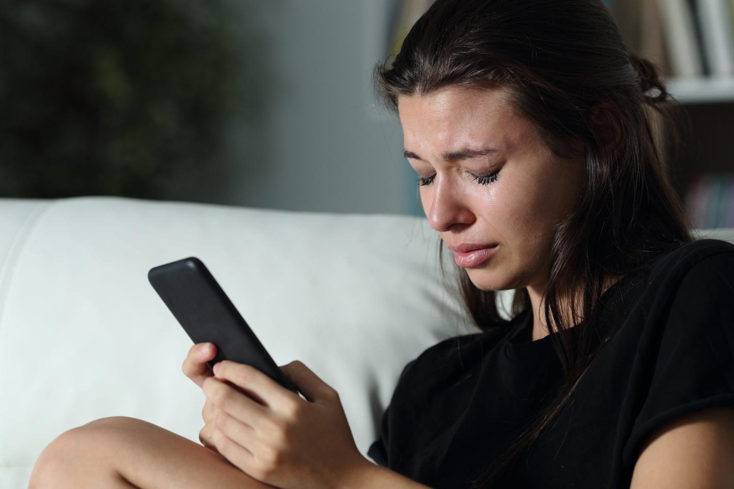 teen girl holding phone while crying