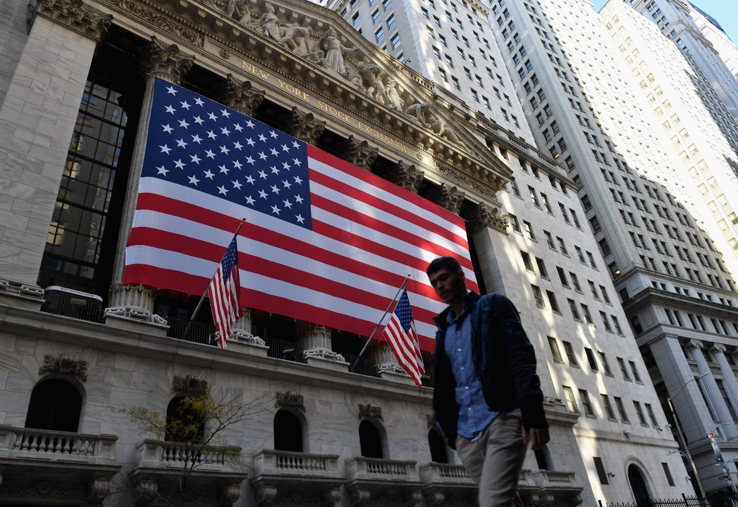 A person walks past the New York Stock Exchange at Wall Street.