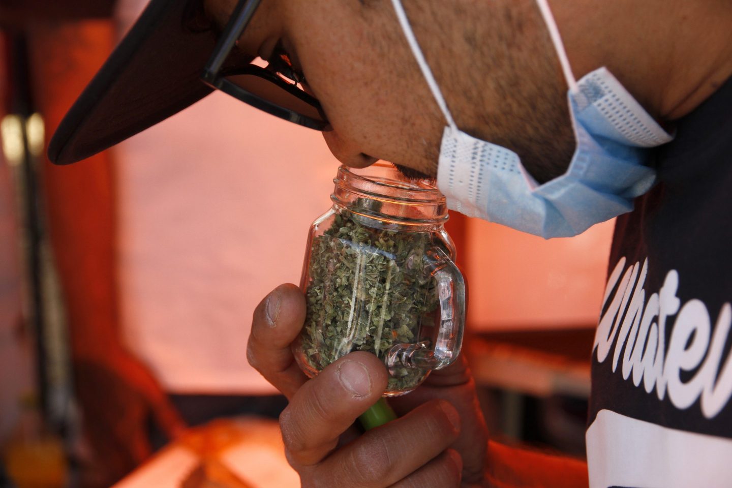 A person smells a jar with marijuana.