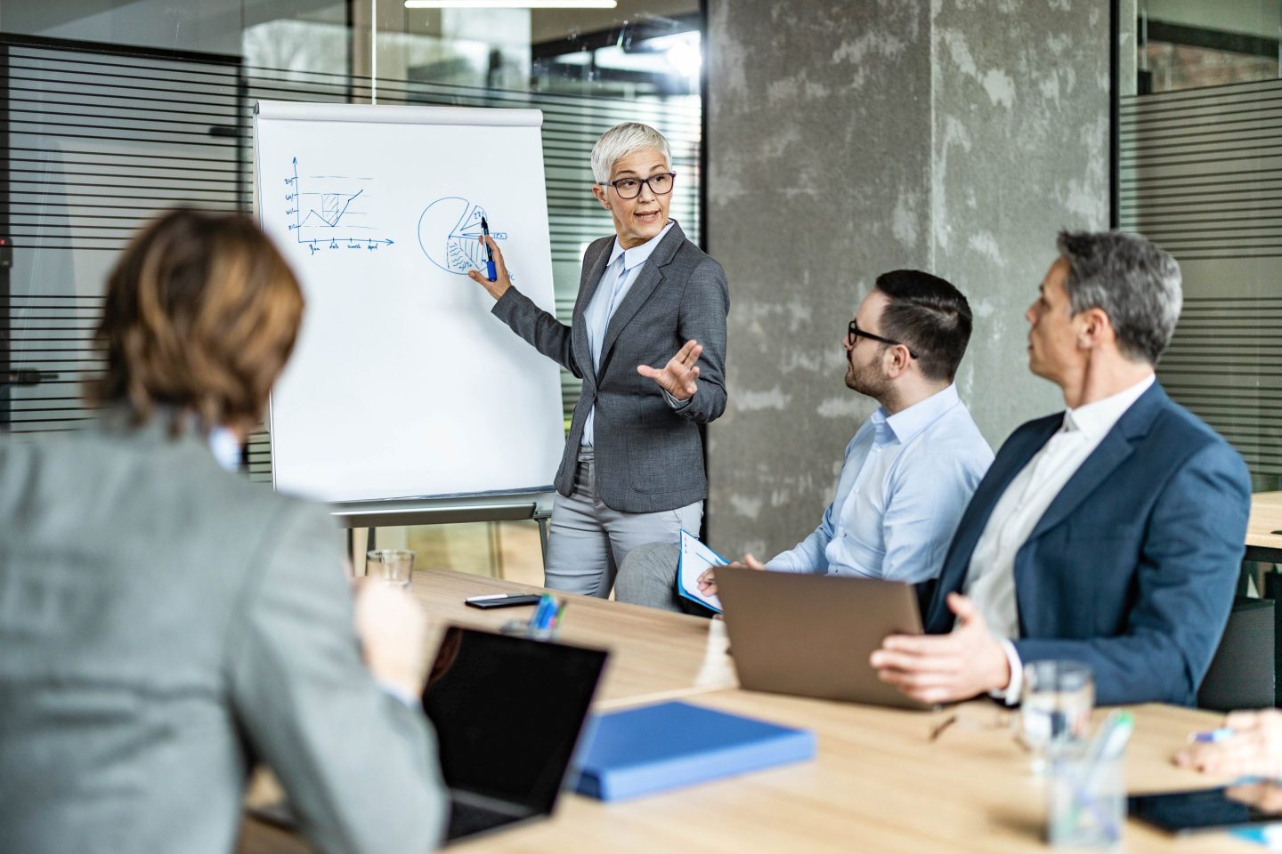 Senior female entrepreneur talking to her colleagues while giving them a business presentation in the office.