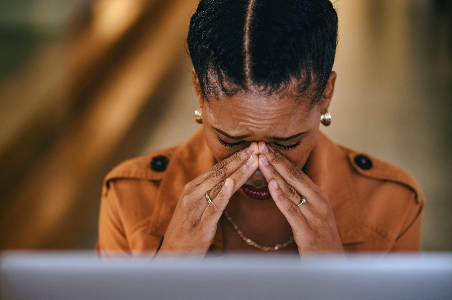 Sad and stressed worker cries at desk.