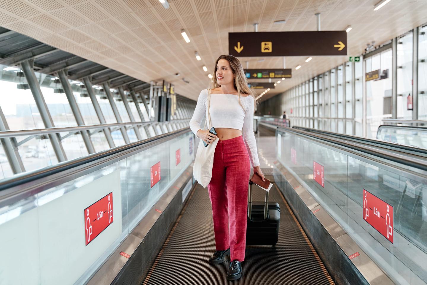 woman walking on an airport treadmill while carrying suitcase