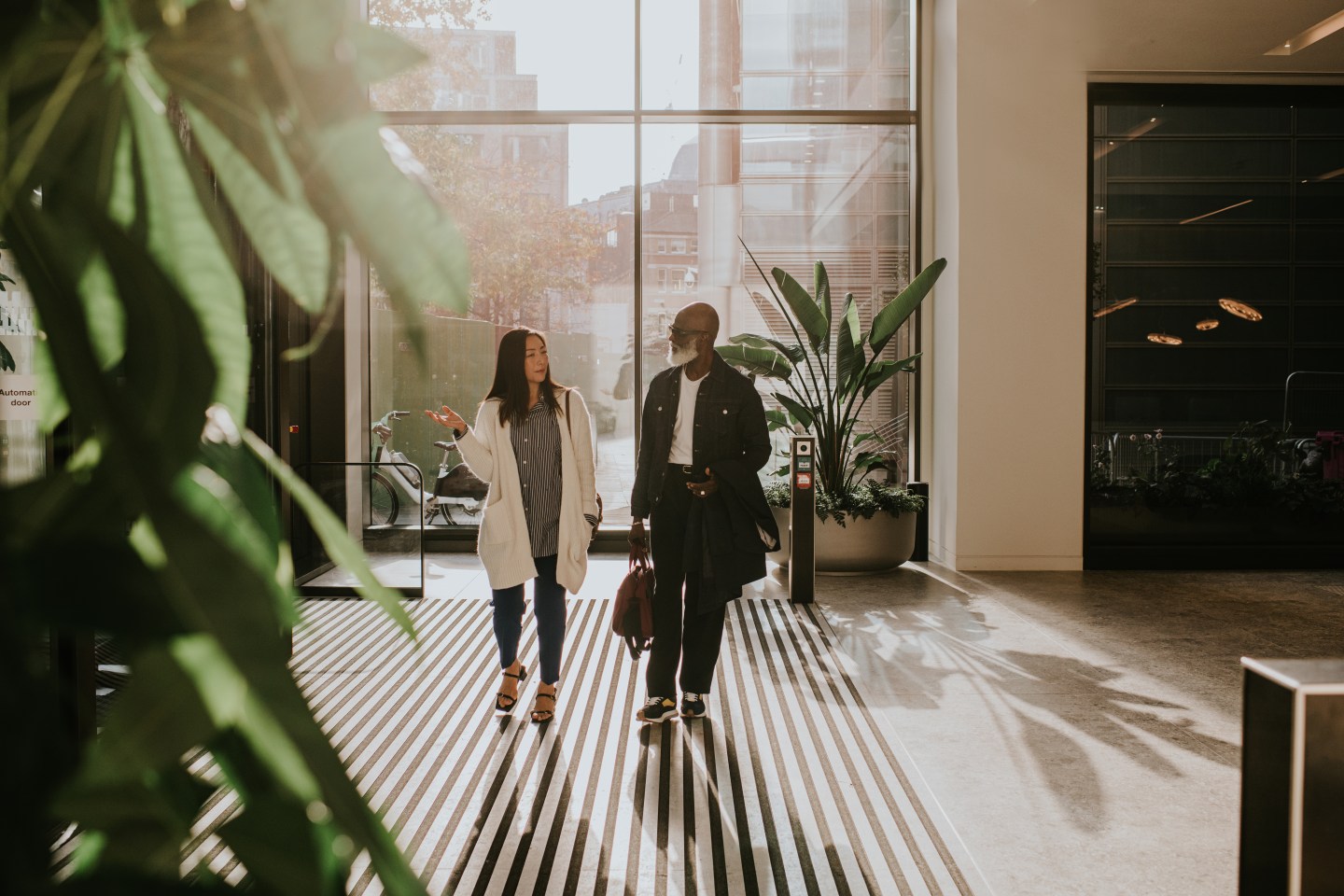 A man and woman enter a large, light filled interior space through rotating doors