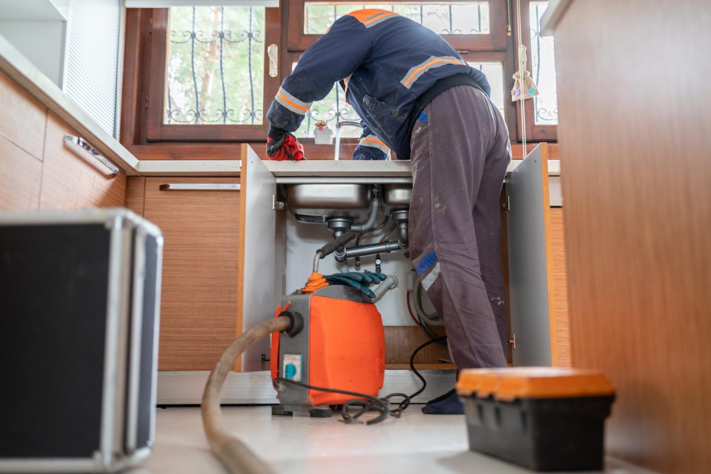 Plumber Unclogging A Kitchen Sink
