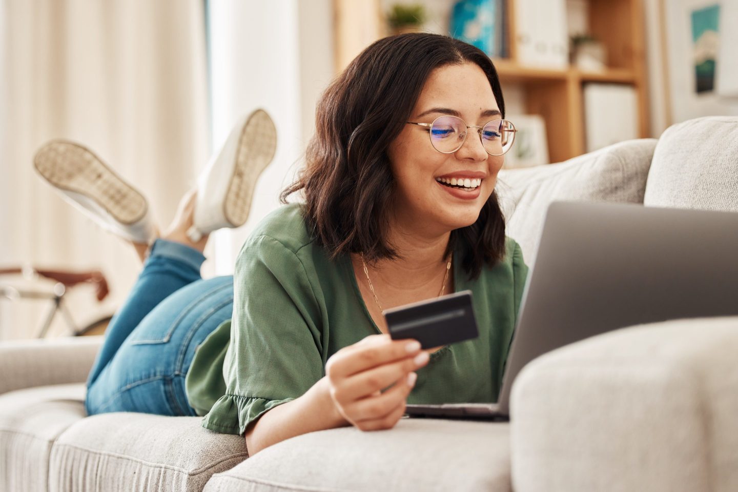 Woman happily using a credit card on the couch.