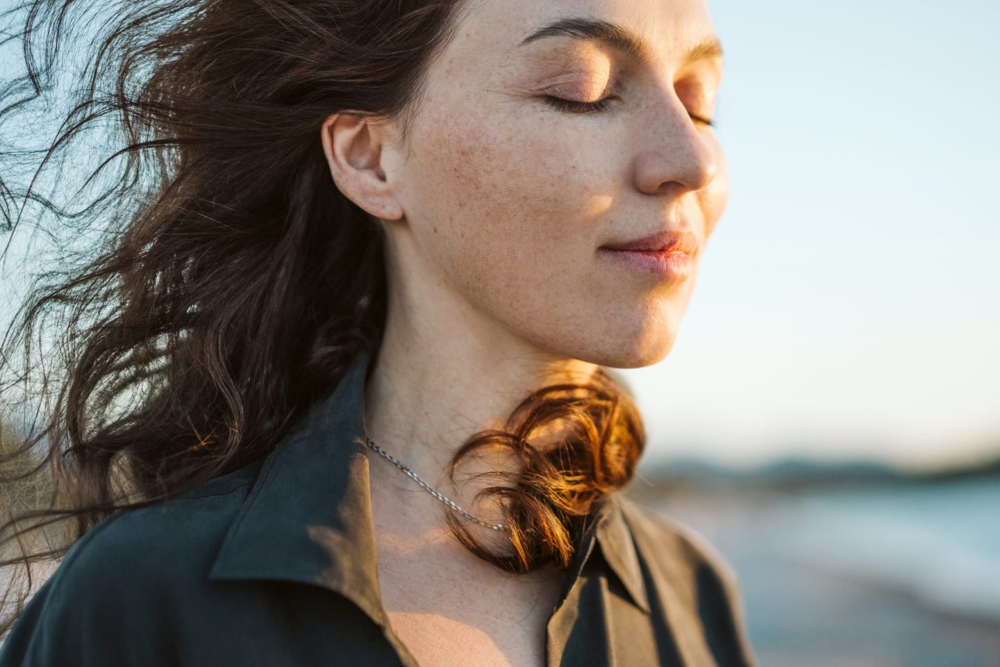 Portrait of a calm woman with hair flying in the wind on the beach.